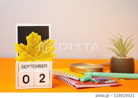Wooden calendar with words September 2nd. Beginning of the school year. New season. Notebooks, flower and yellow leaves. Wooden calendar with words September 2nd. Beginning of the school year. New season. Notebooks, flower and yellow leaves. 118029321