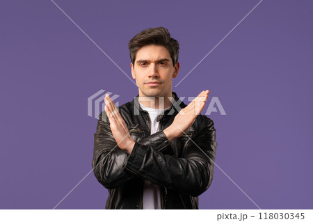 Serious mature 30s man with crossed hands showing forbid sign, refuse gesture. Guy in leather - not, never, rejection on violet studio Serious mature 30s man with crossed hands showing forbid sign, refuse gesture. Guy in leather - not, never, rejection on violet studio 118030345