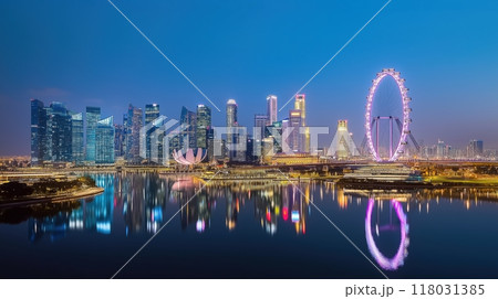 stunning cityscape of Singapore at dusk, featuring the iconic Singapore Flyer and Marina Bay Sands. The vibrant skyline reflects on the calm waters, creating a breathtaking scene. 118031385