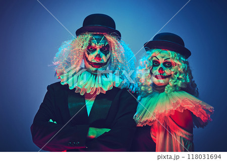 Portrait of creepy clown couple dressed retro style clothes posing looking at camera calmly in neon light against gradient background. 118031694