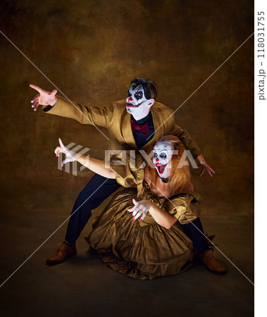 Clowns strike theatrical pose, pointing in unison like they're plotting their next mischief against vintage dark background. 118031755
