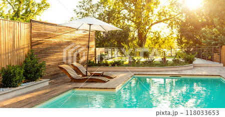 Luxury Pool with Wooden Lounge Chairs and Palm Trees at Dusk. Concept of high-end comfort and relaxation in a modern outdoor space 118033653