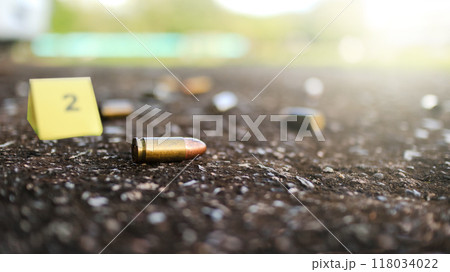 Spent bullet casing lying on dark ground with blur number 2 sign. Concepts of criminal investigations 118034022