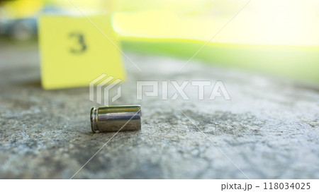 Spent bullet casing lying on dark ground with blur number 3 sign. Concepts of criminal investigations Spent bullet casing lying on dark ground with blur number 3 sign. Concepts of criminal investigations 118034025