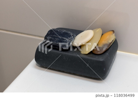 Variety of used soap bars resting in a black soap dish in a bathroom. 118036499