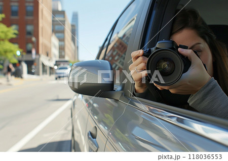 Photographer in a car capturing urban scenes during the day with buildings reflected in the car's side mirror. 118036553