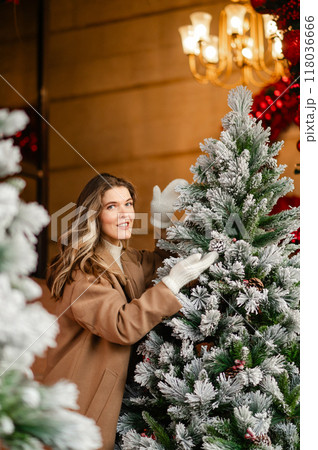 Beautiful woman in a coat and white mittens near the Christmas tree, holiday mood 118036666