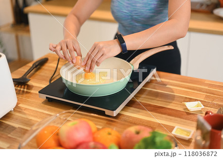 Cropped shot of young woman wearing active ware frying eggs for breakfast in kitchen Cropped shot of young woman wearing active ware frying eggs for breakfast in kitchen 118036872