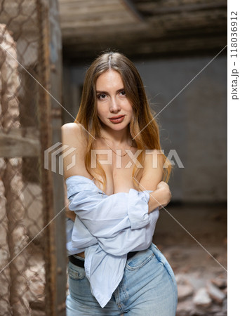 Woman in dropped off shoulders shirt posing near steel mesh fencing inside destroyed building Woman in dropped off shoulders shirt posing near steel mesh fencing inside destroyed building 118036912