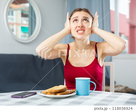 Angry woman covering ears because of loud neighbors 118036924