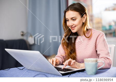 Portrait of a young woman working on a laptop 118036954