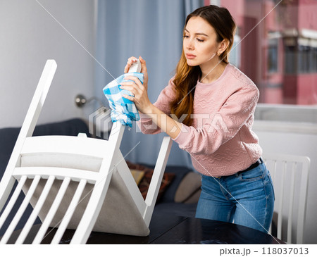 Young woman wipes a chair with a damp cloth Young woman wipes a chair with a damp cloth 118037013