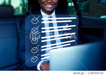 A man in a suit is sitting in a car with a laptop open in front of him A man in a suit is sitting in a car with a laptop open in front of him 118038316