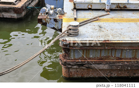 Bollard with Mooring line on rusty pier referred to a post on a ship or quay. Bollard with Mooring line on rusty pier referred to a post on a ship or quay. 118041111