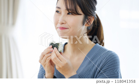 おにぎりを笑顔で食べる女性 おにぎりを笑顔で食べる女性 118041358