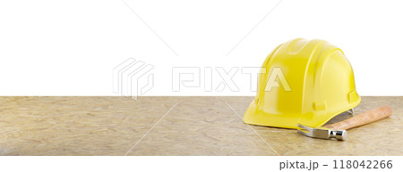 Yellow Construction Hard Hat and Hammer Resting on Particleboard Banner Isolated on a White Background. Yellow Construction Hard Hat and Hammer Resting on Particleboard Banner Isolated on a White Background. 118042266