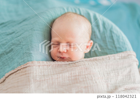 The baby is sleeping peacefully in his cozy nest. Newborn photo session captures the serene innocence and warmth of early moments The baby is sleeping peacefully in his cozy nest. Newborn photo session captures the serene innocence and warmth of early moments 118042321