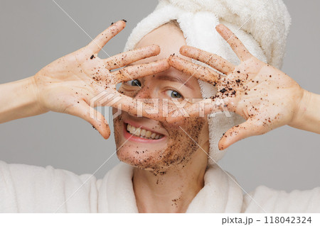Woman enjoying facial skin care, applying black coffee face scrub, concept of rejuvenation and facial skin care 118042324