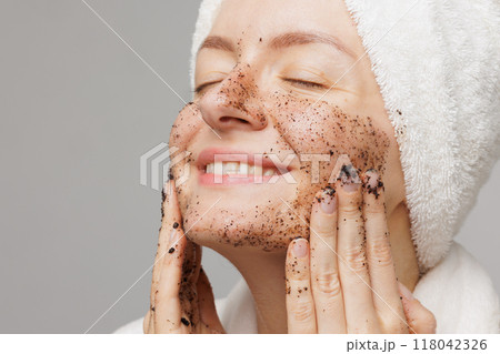 Woman enjoying facial skin care, applying black coffee face scrub, concept of rejuvenation and facial skin care 118042326