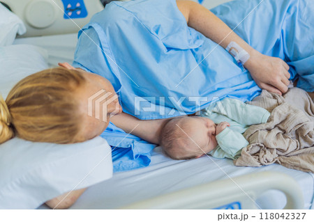 A baby lies with the mother after childbirth, resting peacefully. The serene moment captures the bond between mother and child as they begin their journey together. The hospital environment ensures a 118042327