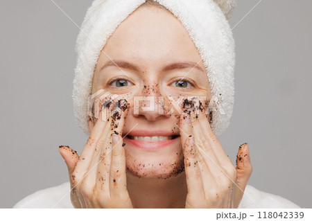 Woman enjoying facial skin care, applying black coffee face scrub, concept of rejuvenation and facial skin care 118042339