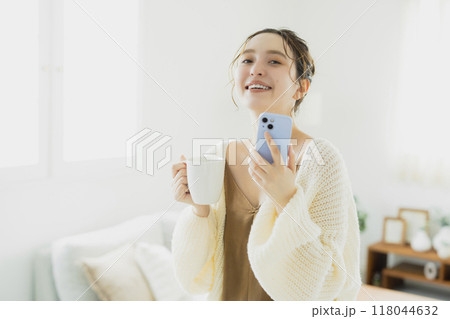 部屋でスマホを見る若い女性　 118044632