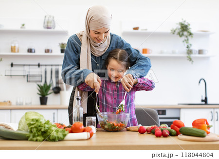 Muslim mother and daughter preparing fresh vegetable salad in kitchen 118044804