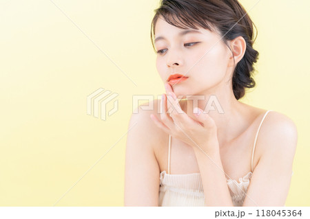 イエローバックでスキンケアをする若い女性 118045364
