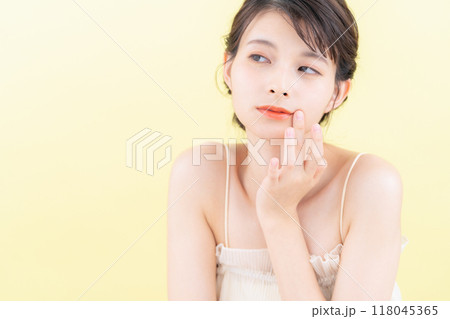 イエローバックでスキンケアをする若い女性 イエローバックでスキンケアをする若い女性 118045365