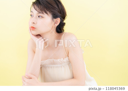 イエローバックでスキンケアをする若い女性 118045369