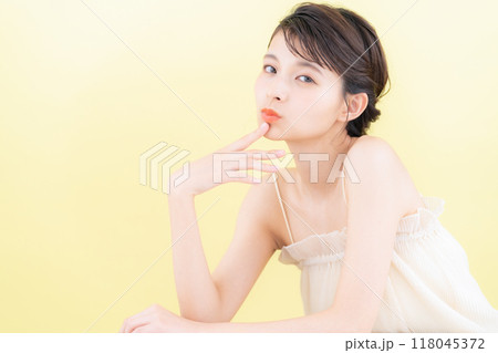 イエローバックでスキンケアをする若い女性 118045372