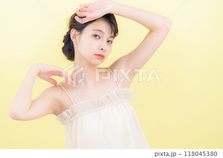 イエローバックでスキンケアをする若い女性 118045380