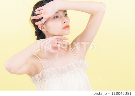 イエローバックでスキンケアをする若い女性 118045381
