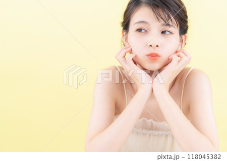 イエローバックでスキンケアをする若い女性 118045382