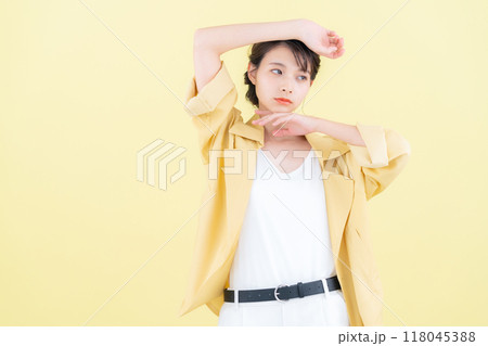 イエローバックでジャケットを着てポーズを取る若い女性 118045388