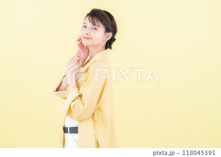 イエローバックでジャケットを着てポーズを取る若い女性 118045391