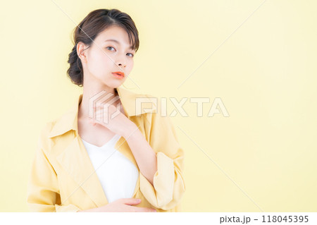 イエローバックでジャケットを着てポーズを取る若い女性 イエローバックでジャケットを着てポーズを取る若い女性 118045395