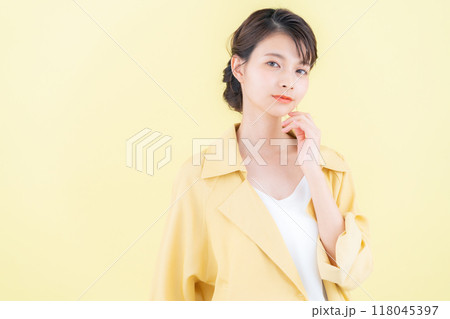 イエローバックでジャケットを着てポーズを取る若い女性 118045397