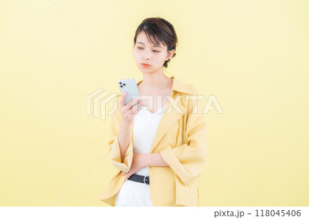 イエローバックでスマホを見る若い女性 118045406
