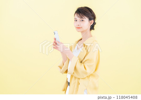 イエローバックでスマホを見る若い女性 イエローバックでスマホを見る若い女性 118045408