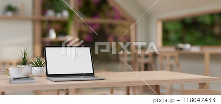 A laptop on a wooden table in a contemporary Scandinavian coffee shop seating area. 118047433