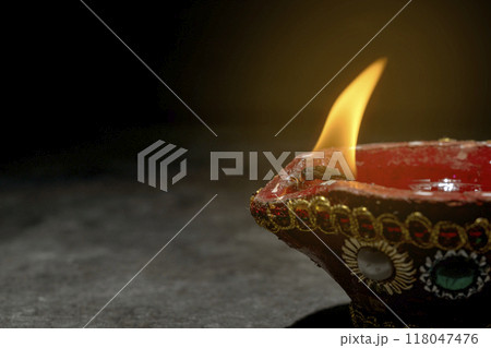 A red and gold decorated pot with a blue and white design sits on a dark surface 118047476