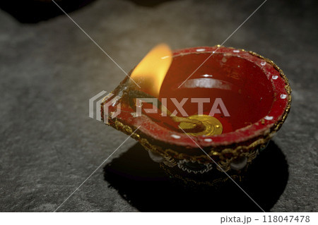 A red and gold decorated pot with a blue and white design sits on a dark surface 118047478