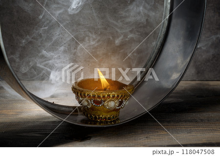 Diya oil lamp on the sieve. The candle is lit and the light is shining through the mesh Diya oil lamp on the sieve. The candle is lit and the light is shining through the mesh 118047508