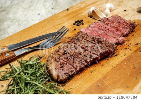 A piece of picanha meat is cut and sitting on a wooden cutting board with a fork and knife A piece of picanha meat is cut and sitting on a wooden cutting board with a fork and knife 118047584