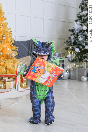 A cute baby character in a dragon costume sits in an egg shell 118048135