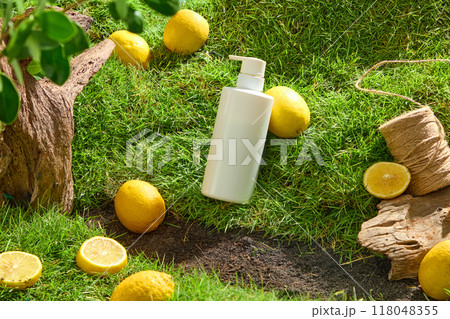 White cosmetic bottle displayed on green grass with fresh lemons and dry twigs. Mockup scene for cosmetic with natural vitamin C from lemon extract. Unlabeled for design White cosmetic bottle displayed on green grass with fresh lemons and dry twigs. Mockup scene for cosmetic with natural vitamin C from lemon extract. Unlabeled for design 118048355