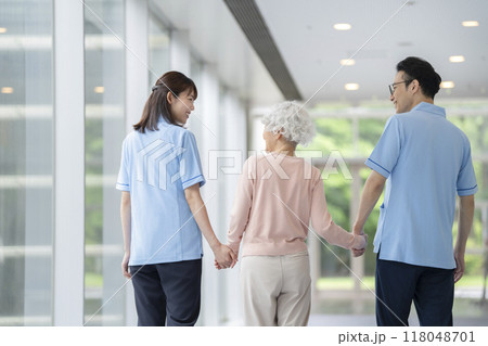 手を繋いで歩くシニア女性と介護スタッフ　後ろ姿 118048701