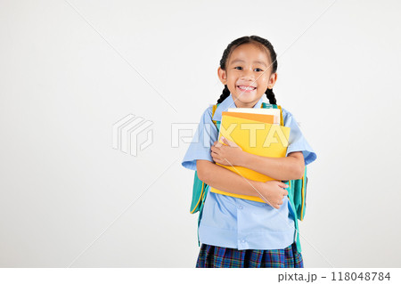 Portrait Asian smiling young girl kids kindergarten holding backpack and hugging books studio shot isolated white background, happy cute little schoolgirl wears school uniform, back to school concept Portrait Asian smiling young girl kids kindergarten holding backpack and hugging books studio shot isolated white background, happy cute little schoolgirl wears school uniform, back to school concept 118048784