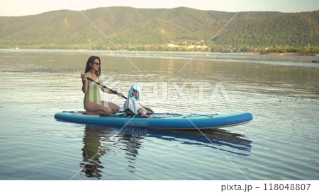Experience the joy of a refreshing summer paddleboarding adventure on serene, calm waters 118048807